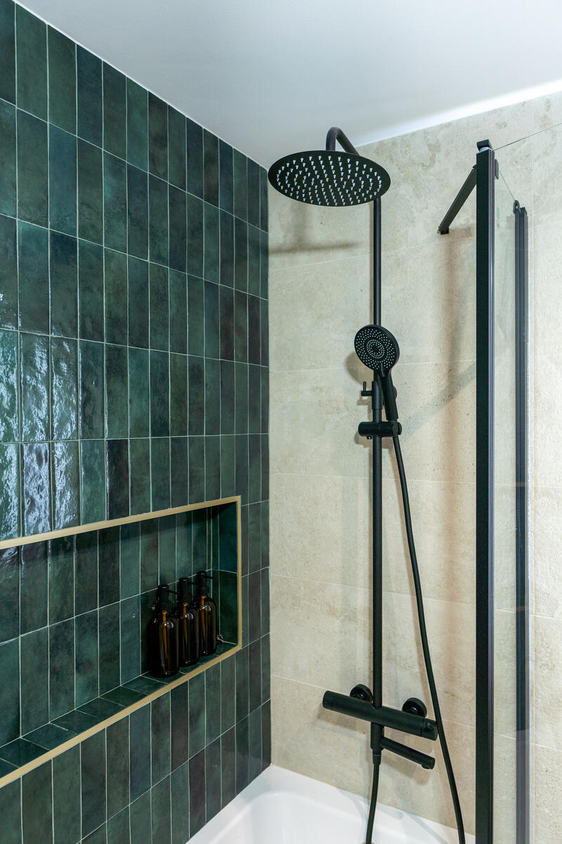 Ducha con azulejos verdes y grifería negra